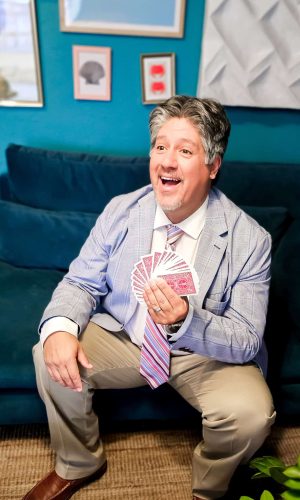 Frank Greer a professional magician, holding a magic card performing for weddings, corporate and special events, blending mind-reading and illusion.