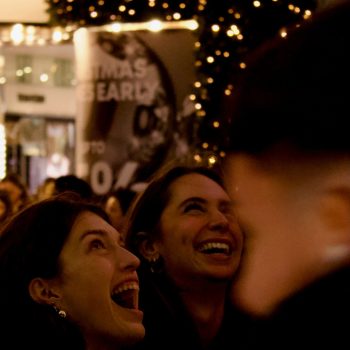 Two young woman laughing and enjoying a show in San Antonio, lights in a decorated outdoor setting