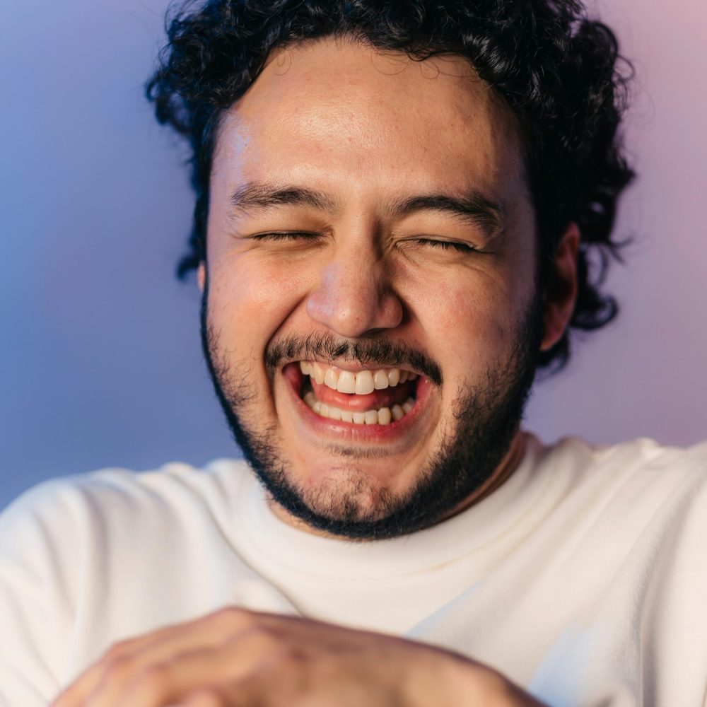 A man in a white shirt laughs joyfully